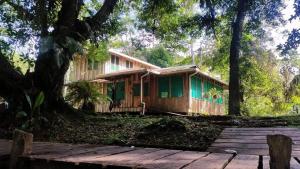 ein Holzhaus im Wald mit einer Holzterrasse in der Unterkunft ESMERALDA LODGE in Siquirres