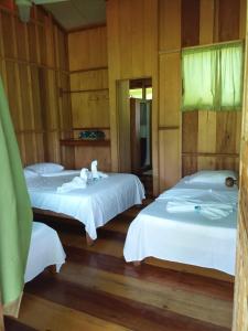 2 Betten in einem Zimmer mit Holzwänden und Holzböden in der Unterkunft ESMERALDA LODGE in Siquirres