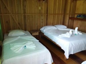 2 Betten in einem Zimmer mit Schwänen darauf in der Unterkunft ESMERALDA LODGE in Siquirres