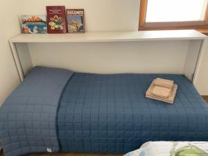 un letto blu in una stanza con mensola di Casa Lucia a Mezzano