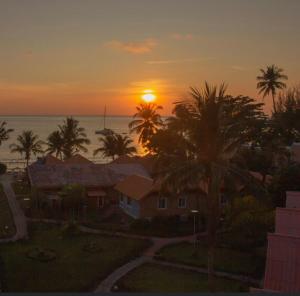 象島的住宿－閣昌島度假酒店，棕榈树和海洋的房屋的日落