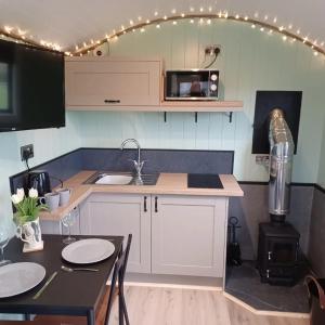 eine Küche mit Theke und Tisch mit Stühlen in der Unterkunft Cwtch Winnie Shepherd's Hut- Pen Cefn Farm Holiday in Abergele