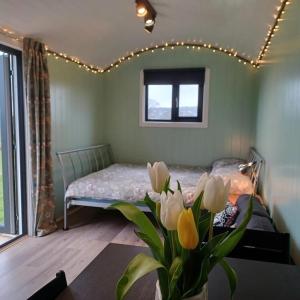 ein Schlafzimmer mit einem Bett und einer Blumenvase in der Unterkunft Cwtch Winnie Shepherd's Hut- Pen Cefn Farm Holiday in Abergele