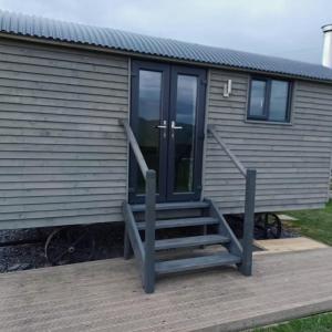 dom z drzwiami i drewnianym tarasem w obiekcie Cwtch Winnie Shepherd's Hut- Pen Cefn Farm Holiday w mieście Abergele