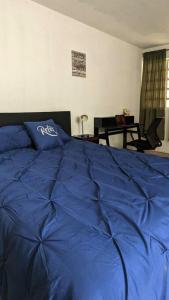 a bed with a blue comforter in a bedroom at Apartment in Colonia Molina in Quetzaltenango
