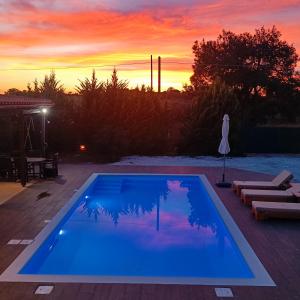 een blauw zwembad met een zonsondergang op de achtergrond bij Drosoula Villa 3bdr private swimming pool in Chorafakia