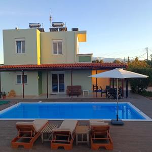 een zwembad met stoelen en een parasol naast een huis bij Drosoula Villa 3bdr private swimming pool in Chorafakia