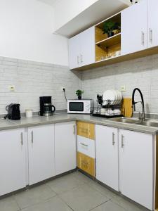 een keuken met witte kasten en een magnetron bij Appartement ethnique cosy in Douala
