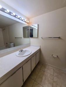 uma casa de banho com um lavatório e um espelho em Presidential Golfview Condominiums em West Palm Beach