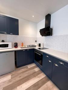una cocina con armarios azules y encimeras blancas en T2 splendide, 3 min gare Mulsant, en Roanne