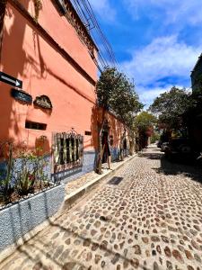 a person walking down a street next to a pink building at Casa Camellia in San Miguel de Allende
