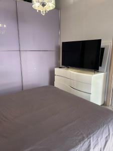 una camera da letto con TV a schermo piatto su una cassettiera bianca di Sarde a Palau