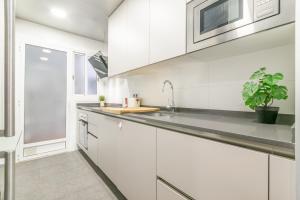 uma cozinha com armários brancos e um lavatório em VALLH em Barcelona