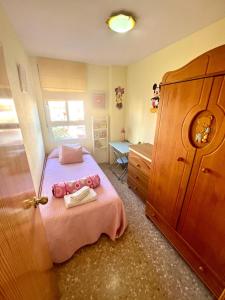 ein kleines Schlafzimmer mit einem rosa Bett und einem Schreibtisch in der Unterkunft Apartamento en la Playa Canet, muy cerca de Valencia in Canet d'en Berenguer