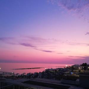a sunset over the water with a group of chairs at Lotus - Apartment sul mare con giardino in Lido di Ostia