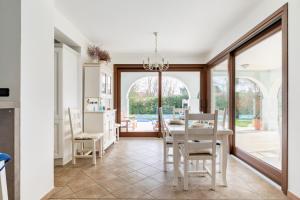 a kitchen and dining room with a table and chairs at Albarella Family Villa with Private Pool and Garden in Isola Albarella