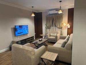 a living room with two couches and a flat screen tv at شقق روز الفندقية دخول ذاتي in Al Khobar