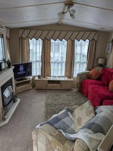 uma sala de estar com um sofá e uma televisão em luxury home from home caravan em Ingoldmells