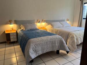 a bedroom with two beds and a night stand with lamps at Casa Dei Girasoli in Cabo San Lucas
