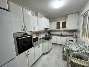 リベイラにあるAlquiler Vacacional en Ribeiraの白いキャビネットとテーブル付きのキッチンが備わります。