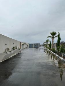 un aparcamiento vacío con palmeras y un edificio en منتجعات الريف بلس, en Ḩajlah