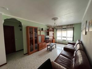 a living room with a leather couch and a tv at Alquiler Vacacional en Ribeira in Ribeira