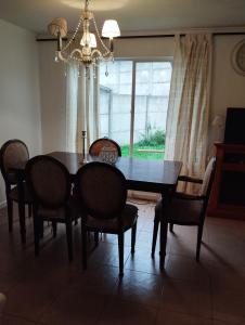 einen Esstisch mit Stühlen und einem Kronleuchter in der Unterkunft Casa 3 dormitorios 3 baños Osorno in Osorno