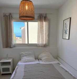 uma cama num quarto com uma janela e um candeeiro em Saint Aygulf - a 250m de la mer- 3 pieces 45m2 em Saint-Aygulf
