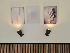 two lights on a white wall with pictures at Lazy Olives in Tongeren