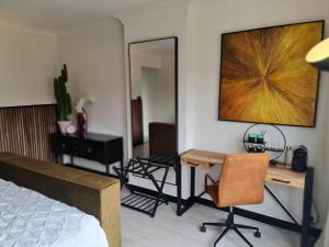 a bedroom with a bed and a desk and a mirror at Lazy Olives in Tongeren