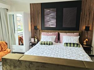 a bedroom with a large bed with pink pillows at Lazy Olives in Tongeren