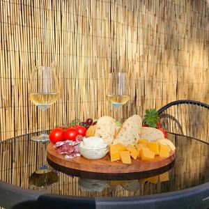 a table with a plate of cheese and wine glasses at Luxe Hottub Huisje Bij het Veen op de rand van het Bargerveen Drenthe in Weiteveen