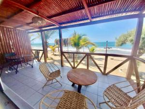 a porch with chairs and a table and a view of the beach at Casuarinas del Mar Habitacion Playa in Canoas De Punta Sal