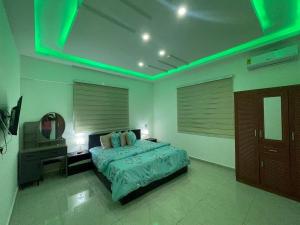 a bedroom with a bed with a green light at Amazing Grace Apartment in Cape Coast