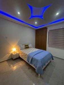 een slaapkamer met een bed met blauwe verlichting aan het plafond bij Amazing Grace Apartment in Cape Coast