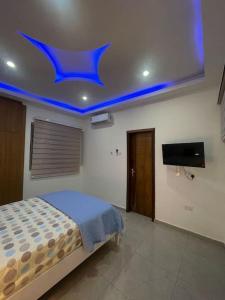 een slaapkamer met een bed en een blauw plafond bij Amazing Grace Apartment in Cape Coast