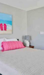 a bedroom with a white bed with a pink pillow at Summer Sands Lodge Unit 2 in Flagler Beach