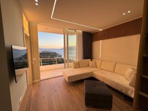 a living room with a couch and a large window at Sea Scape Apartment 3 in Vlorë