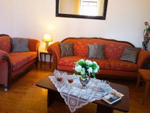 a living room with orange couches and a coffee table at The Old Well, Spacious House in North Corfu in Perítheia