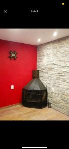 una habitación con una pared roja y una TV negra en La Caprichosa, en San Luis