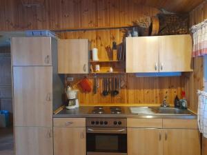 a kitchen with wooden cabinets and a stove and a sink at Letten in Brograngen