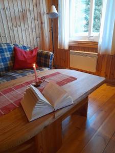 an open book on a table with a candle on it at Letten in Brograngen