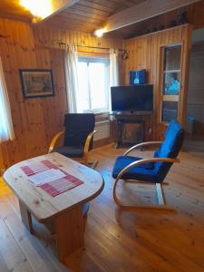 a living room with a table and chairs and a television at Letten in Brograngen