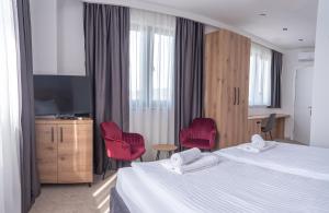 a hotel room with a bed and two red chairs at Hotel Sistems in Banja Luka