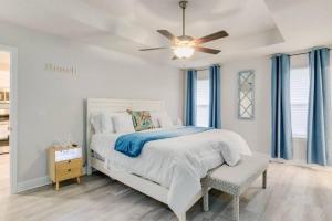 Retreat at the Oasis في بينساكولا: غرفة نوم بيضاء مع سرير ومروحة سقف