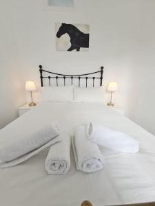 a white bed with towels and a picture of a horse at Charming House in City Centre in Dublin
