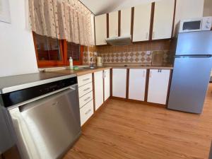 cocina con armarios blancos y nevera de acero inoxidable en Apartment With the Sea View en Basina