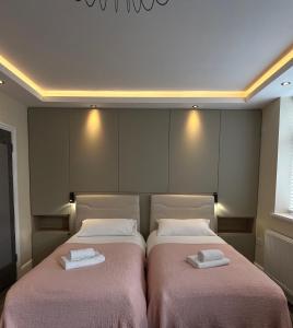 ロンドンにあるブティック アパートメンツのピンクのシーツが備わる客室内のベッド2台