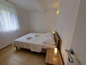 a small white bedroom with a bed and a window at Apartments Maslina in Baška