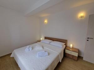 sypialnia z białym łóżkiem i ręcznikami w obiekcie Apartments Maslina w Bašce